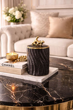 Decorative candle holder on a marble table with a Chanel book and flowers in the background.