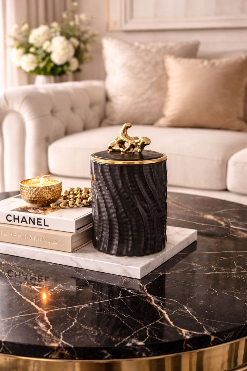 Decorative candle holder on a marble table with a Chanel book and flowers in the background.