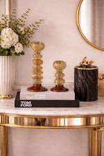 Decorative items on a marble table with a gold frame, including a vase of flowers, books, and a small sculpture.