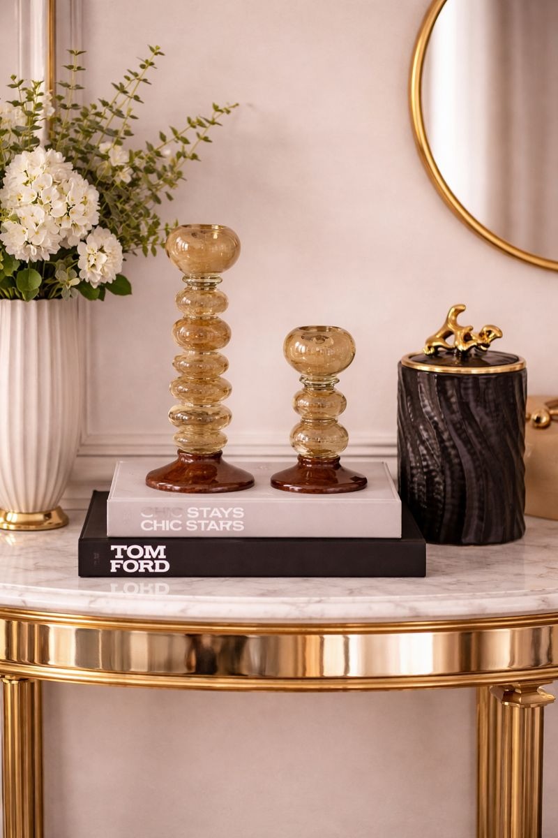 Decorative items on a marble table with a gold frame, including a vase of flowers, books, and a small sculpture.