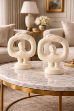Two decorative statues on a marble table in a living room setting.