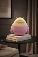 Pink plush toy with a light on top of books on a dark surface