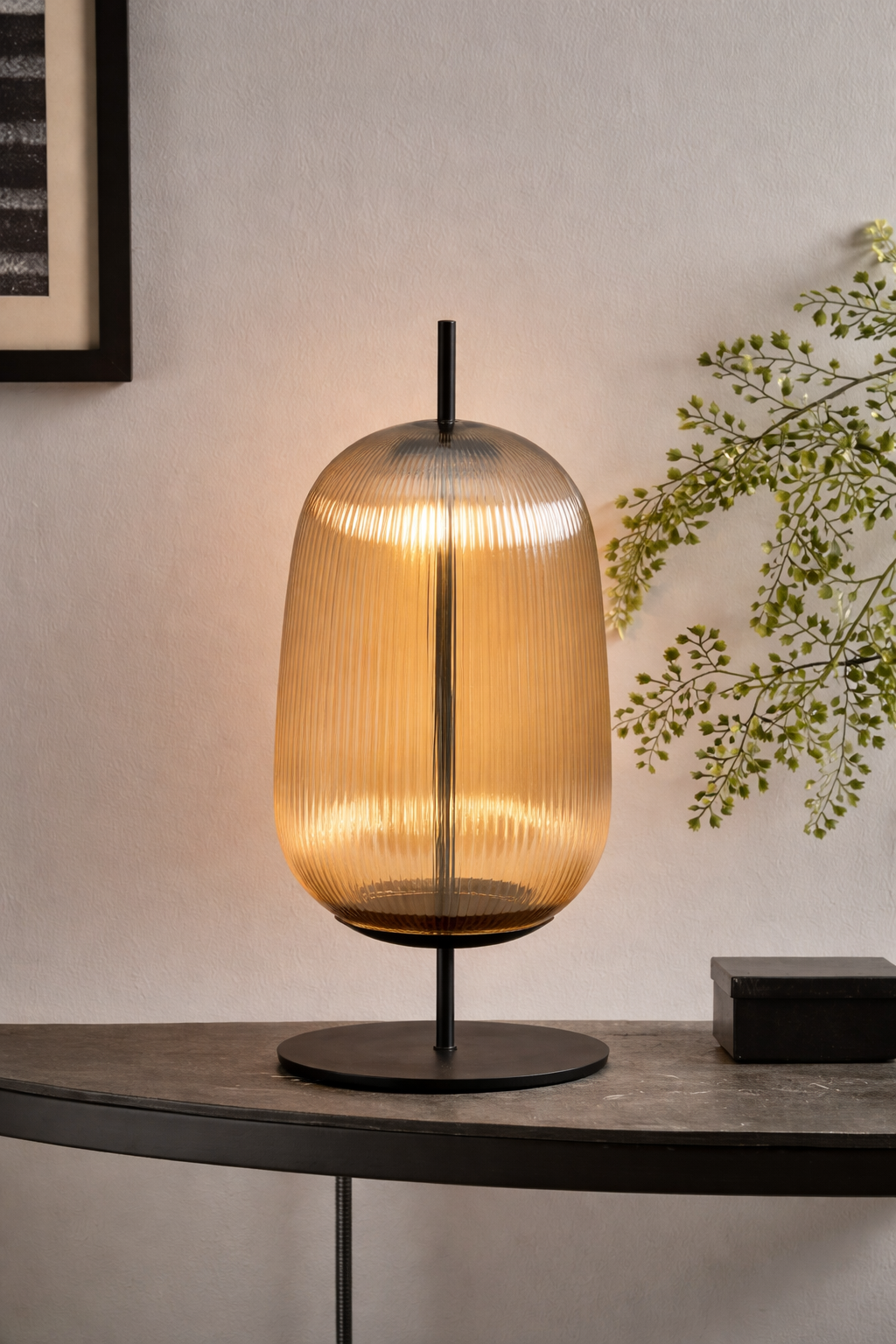 Modern table lamp with a glass shade on a dark surface, with a light background.